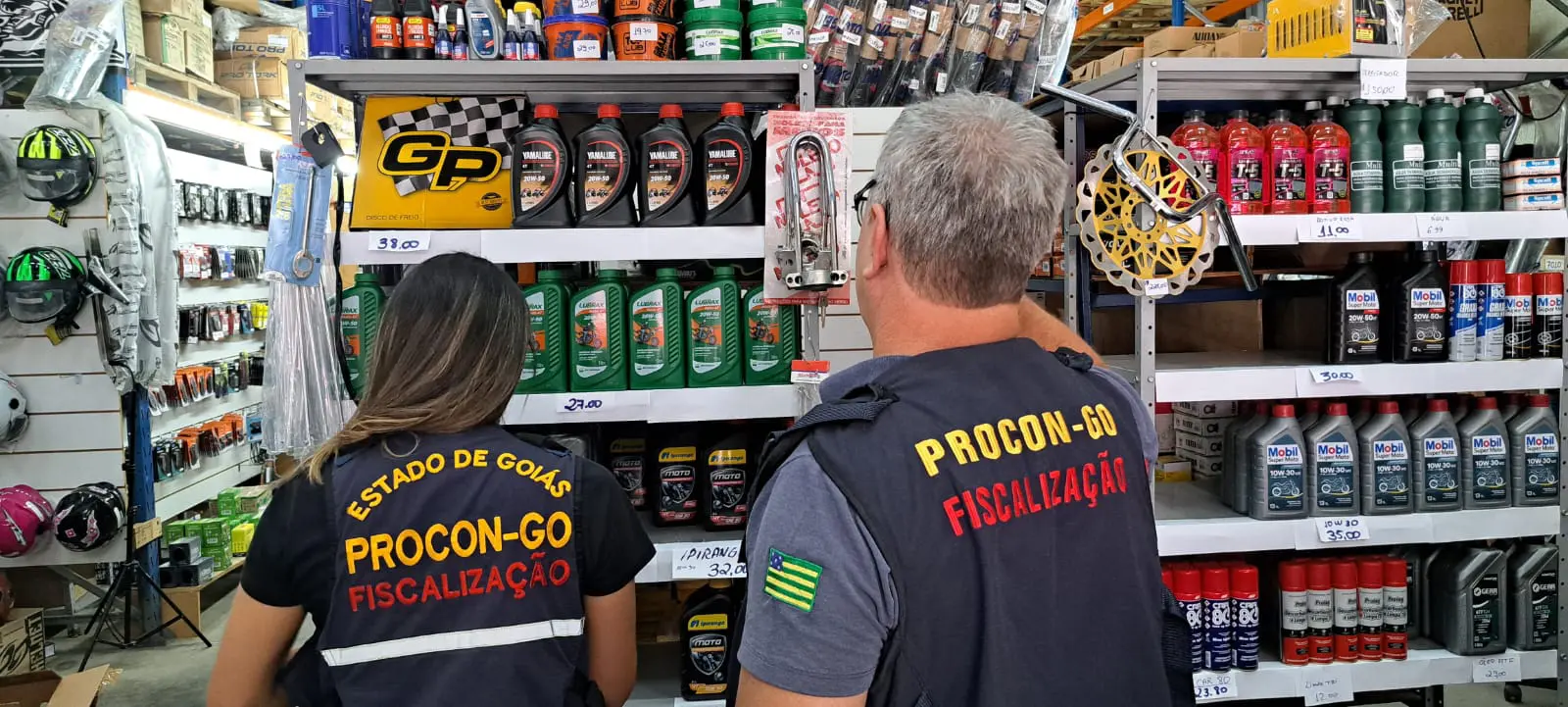 Foto de dois fiscais do Procon verificando óleo de motor