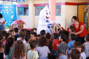 Foto do Zé Gotinha com várias crianças em uma escola de Aparecida de Goiânia