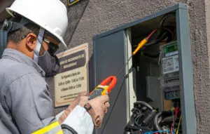 Foto de um funcionário da área elétrica fazendo manutenção.