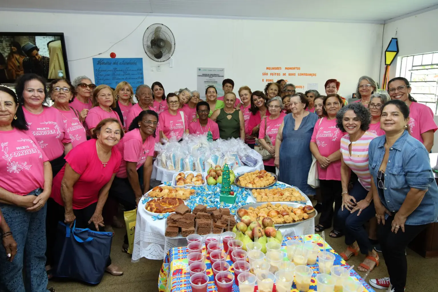 Foto de muitas pessoas em volta de uma grande mesa repleta de comida.