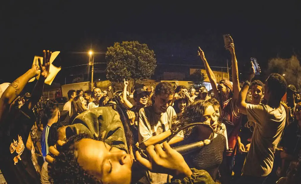 Foto de várias pessoas reunidas em evento de rimas e música.