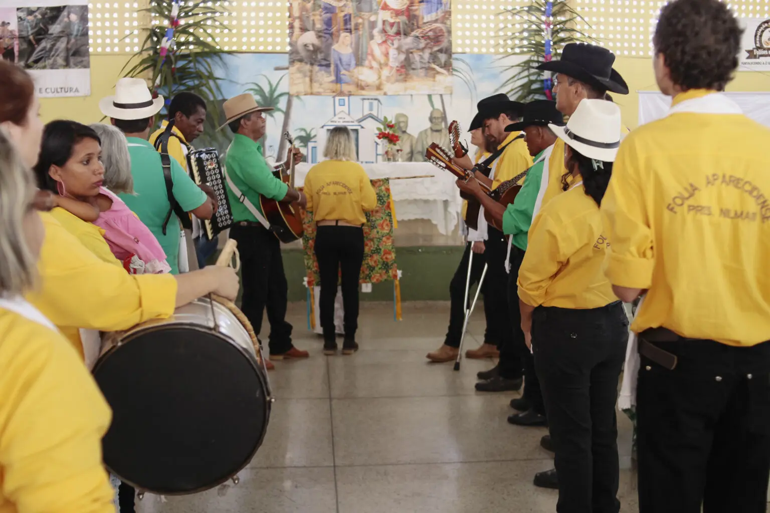 Foto de grupo de pessoas que participam de evento religioso, carregando instrumentos musicais e celebrando tradição cultural e espiritual.