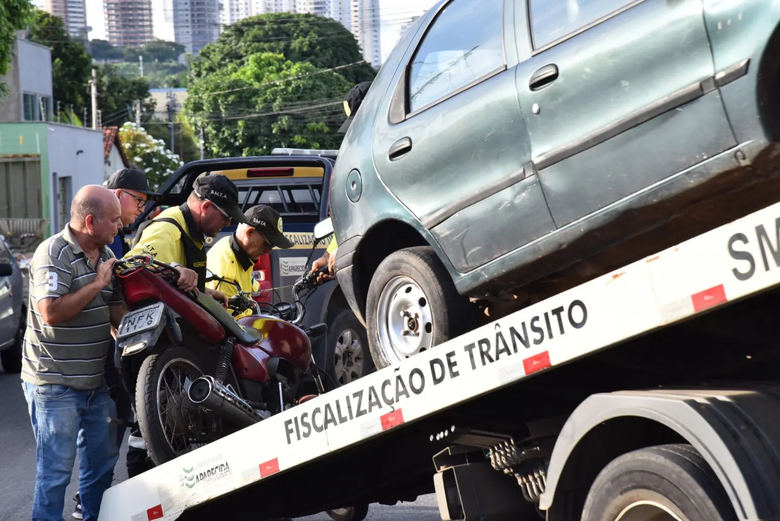 Agentes de trânsito removem veículos durante fiscalização em área urbana, utilizando caminhão-guincho.