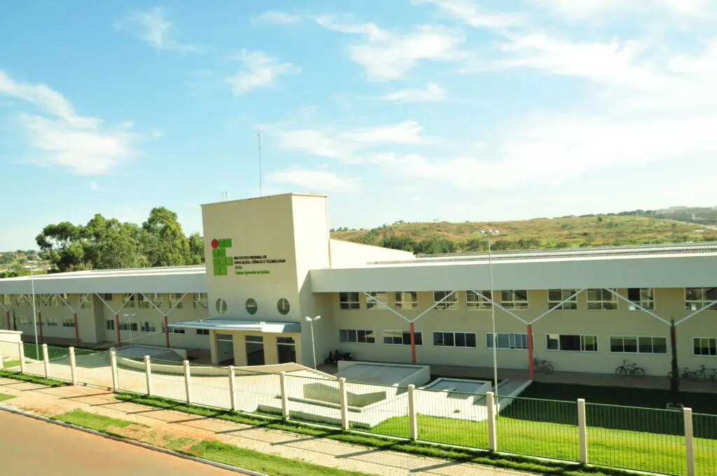 Fachada do Instituto Federal de Goiás (IFG), com arquitetura moderna, cercada por gramados e localizada em uma área tranquila com paisagem de colinas ao fundo.