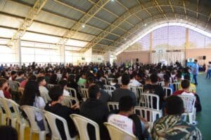 Foto com vários estudantes de Aparecida de Goiânia dentro de um ginásio assistindo uma apresentação