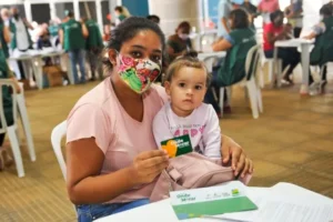 Foto de uma mãe com sua filha recebendo seu cartão