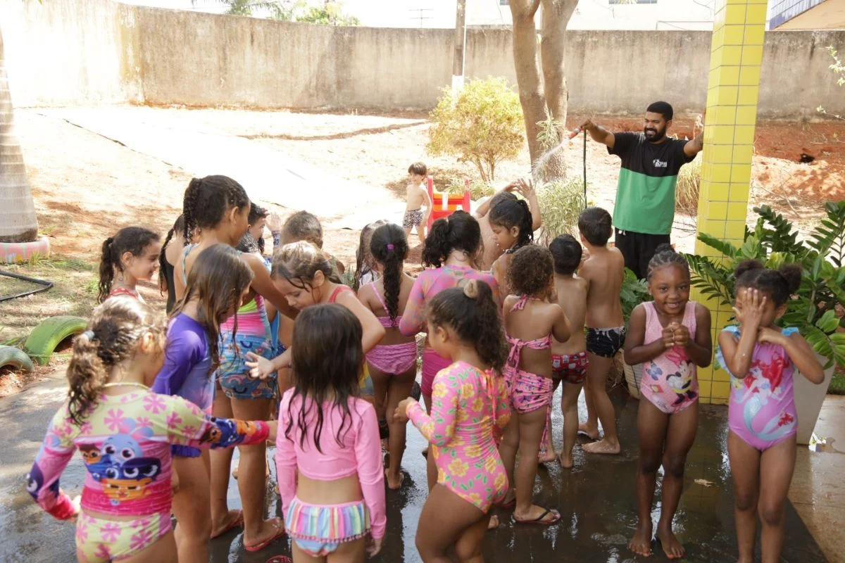 Foto das crianças tomando banho de mangueira