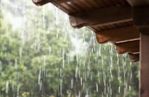 Foto de chuva escorrendo pelo telhado de uma casa.