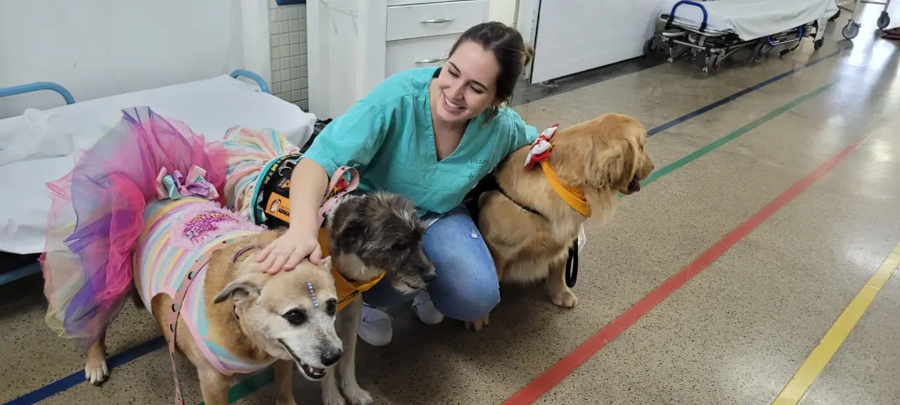 Foto de funcionária acompanhada dos pets em ação no hospital.