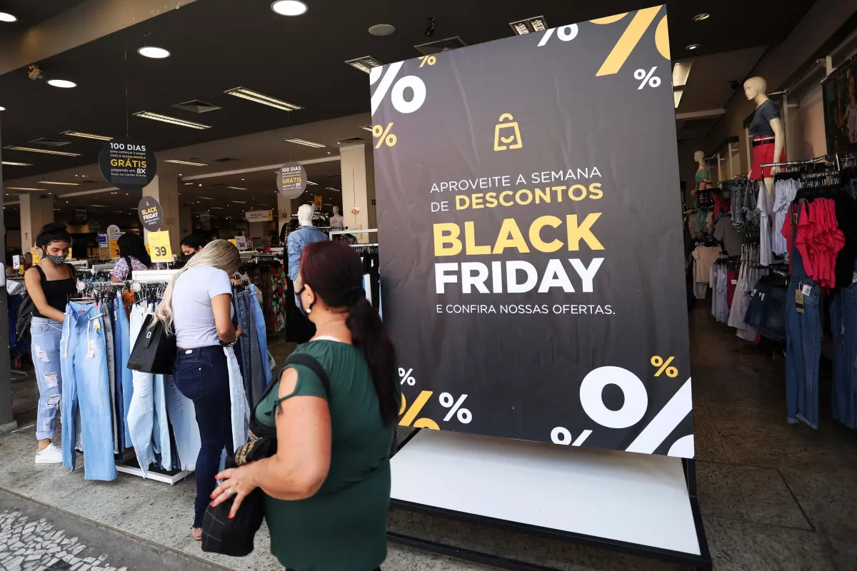 Foto de uma pessoa andando em frente de loja com cartazes de black friday.